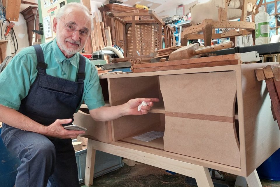 Alain Geisz devant le meuble qu'il a dû réaliser lors de son CAP.